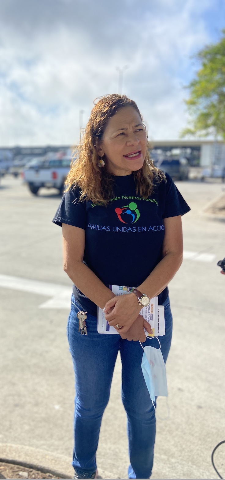 Miriam Romero, promotora de salud con la organización Familias Unidas en Acción, quien usa camiseta azul marino de la organización y pantalones de mezclilla, habla con un trabajador de restauración de desastres. Romero distribuyó máscaras aprobadas por NIOSH de forma gratuita y folletos sobre toxinas en el lugar de trabajo a los jornaleros que esperaban trabajo en el estacionamiento de Lowe's en Nueva Orleans. (María Inés Zamudio/ Center for Public Integrity)